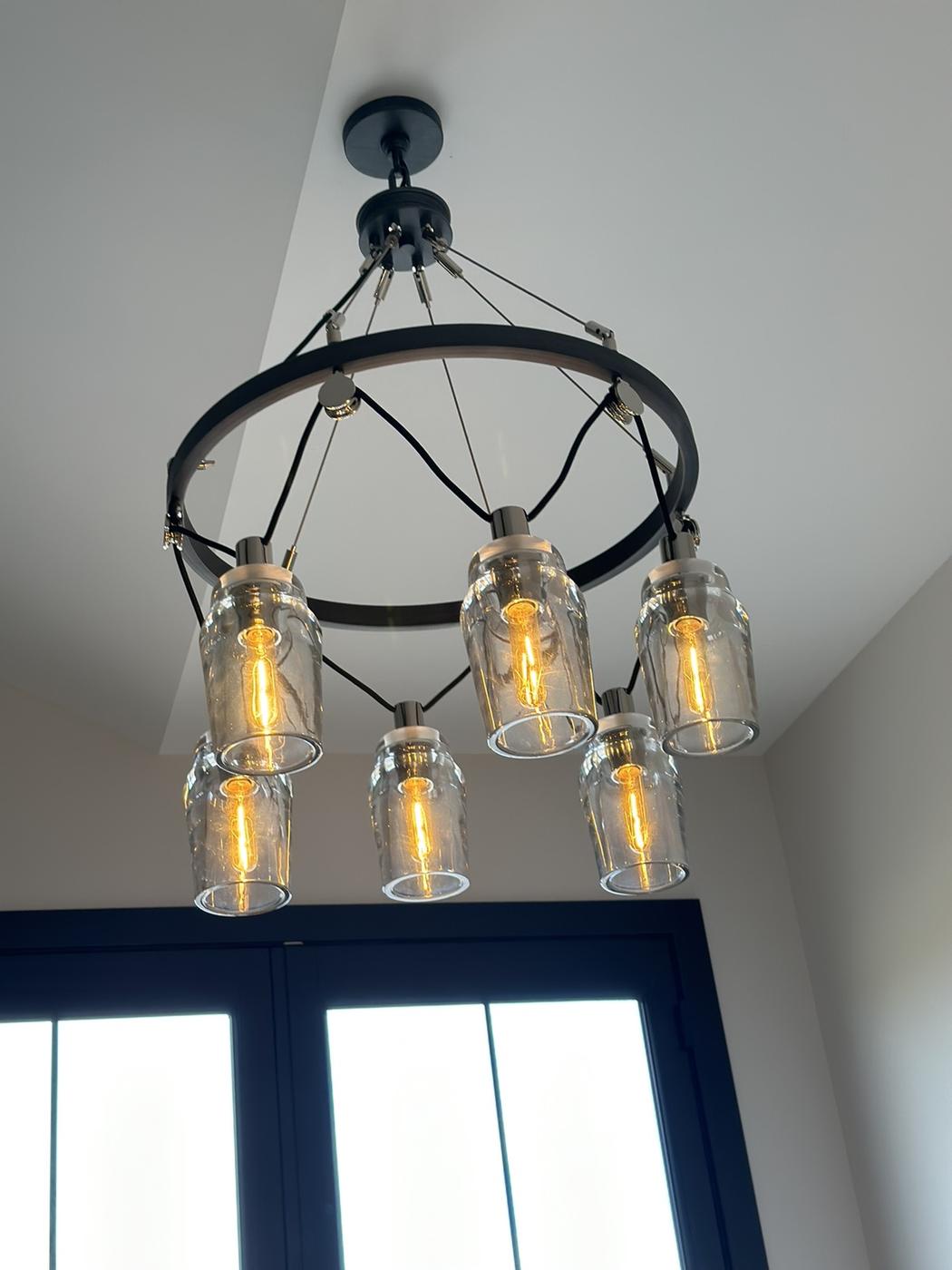 Six-light chandelier with jar shades hung near tall windows